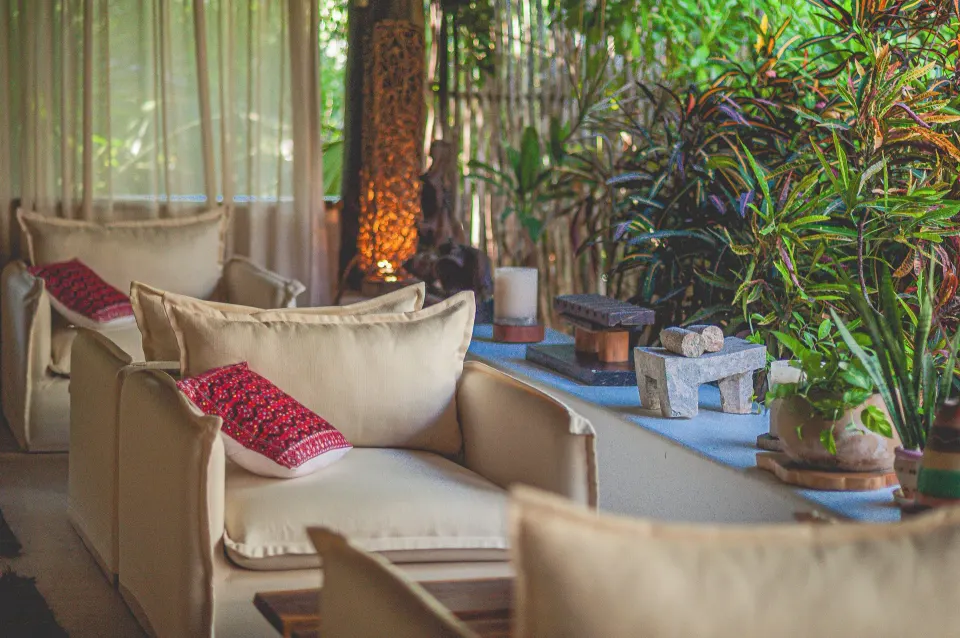 Relaxing covered lounge area with cushioned armchairs and lush plants at The Beach Tulum