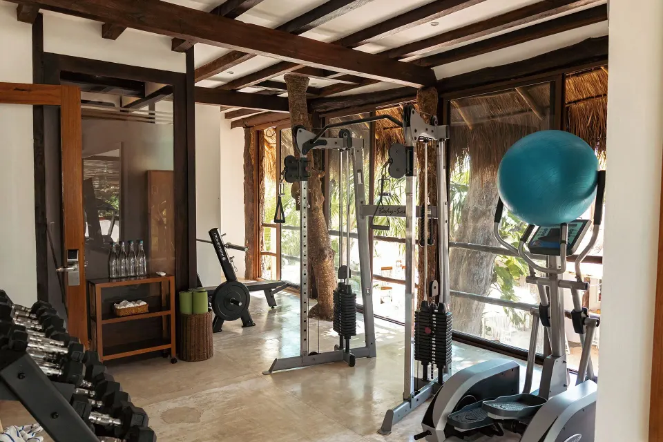 Bright gym area with exercise machines and fitness ball at The Beach Tulum