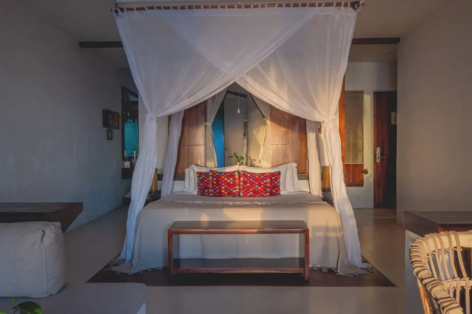 Canopy king bed with mosquito netting in a guest room at The Beach Tulum