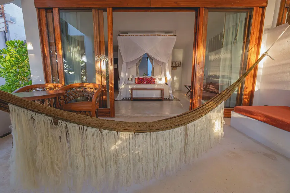 Private patio with fringe hammock facing a canopy bed at The Beach Tulum