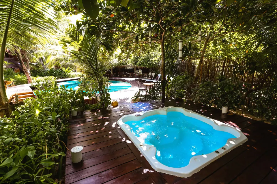 Private hot tub on a wooden deck framed by greenery at The Beach Tulum