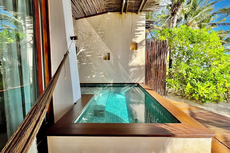 Private plunge pool with wooden trim beside a suite and a hammock at The Beach Tulum