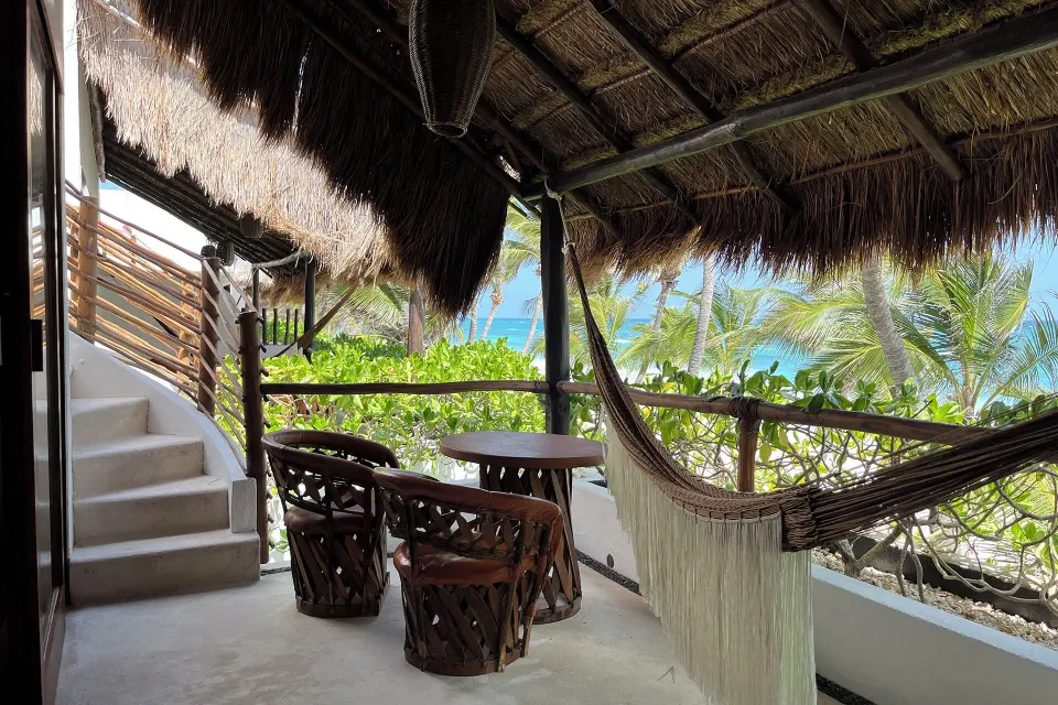 Thatched-roof balcony with hammock and table overlooking palms and ocean at The Beach Tulum