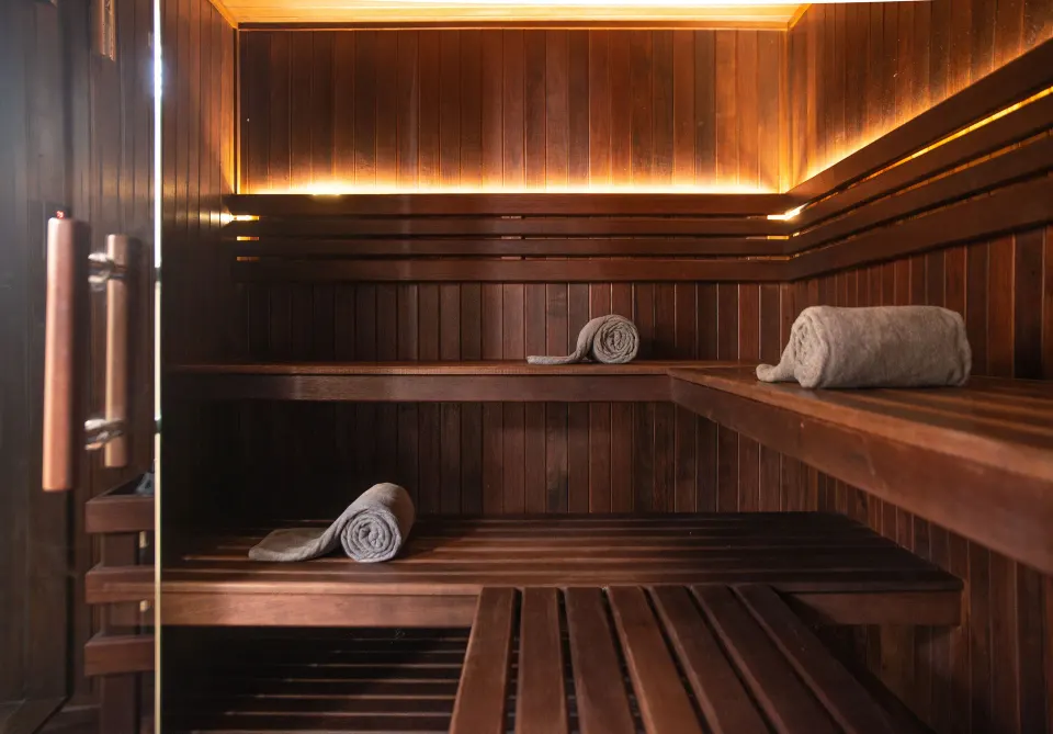 Wood-paneled sauna interior with rolled towels at The Beach Tulum