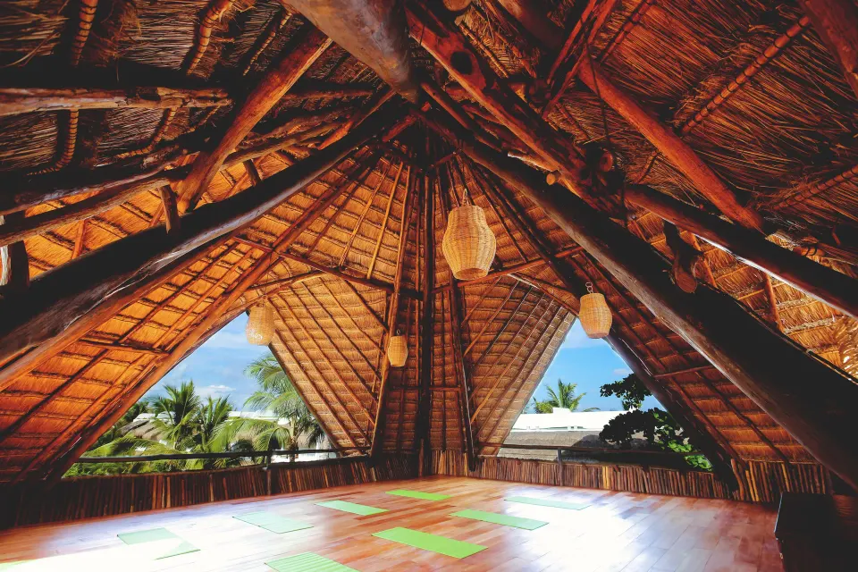 Thatched-roof yoga shala with wooden floor and mats at The Beach Tulum