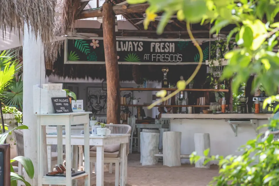 Outdoor beachside bar and counter shaded by a thatched roof at The Beach Tulum