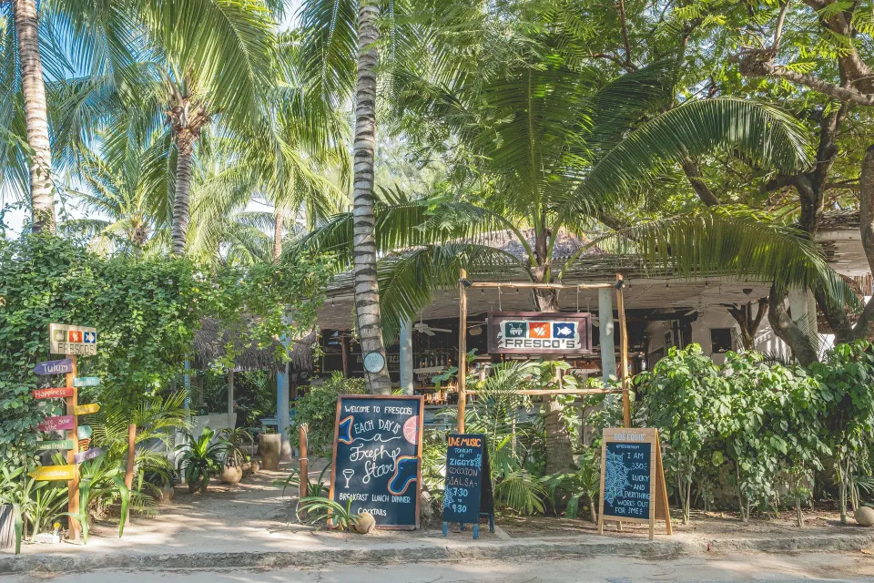 Shaded restaurant entrance with chalkboard menus at The Beach Tulum