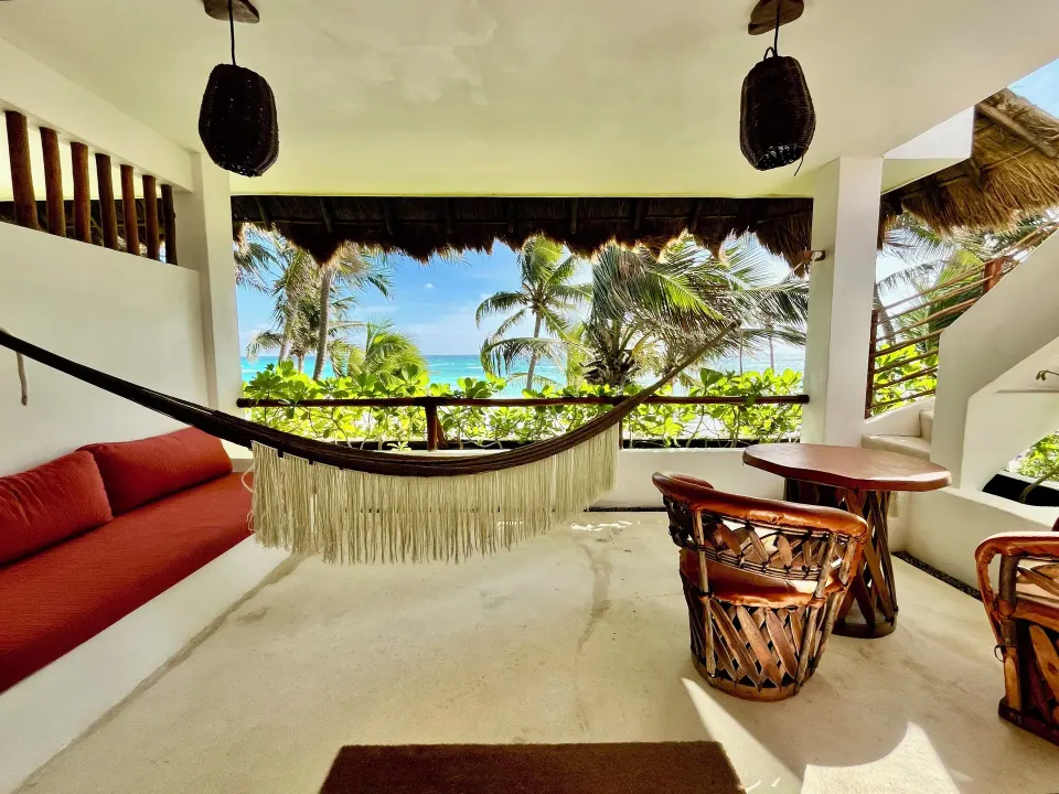 Covered terrace with hammock and wicker chairs facing the beach at The Beach Tulum
