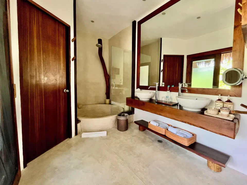 Wide view of bathroom with double sinks and round tub in a Beachfront Rooftop room at The Beach Tulum