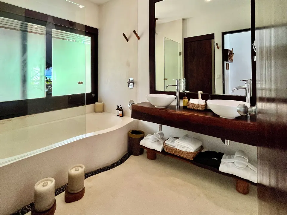 Bright bathroom with twin sinks and tub in a Beachfront Room at The Beach Tulum