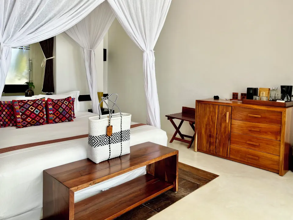 Bedroom seating area and wooden dresser in a Deluxe Room at The Beach Tulum