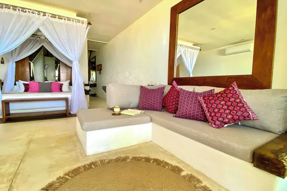 Junior suite interior with sofa and four-poster bed at The Beach Tulum