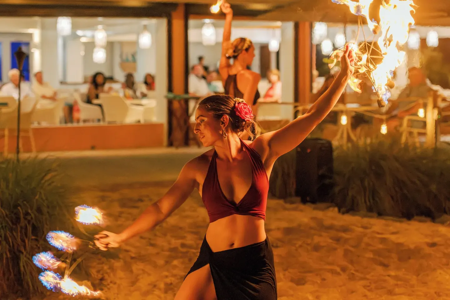 Fire dancer performing on sand near diners at The Buccaneer Beach & Golf Resort.