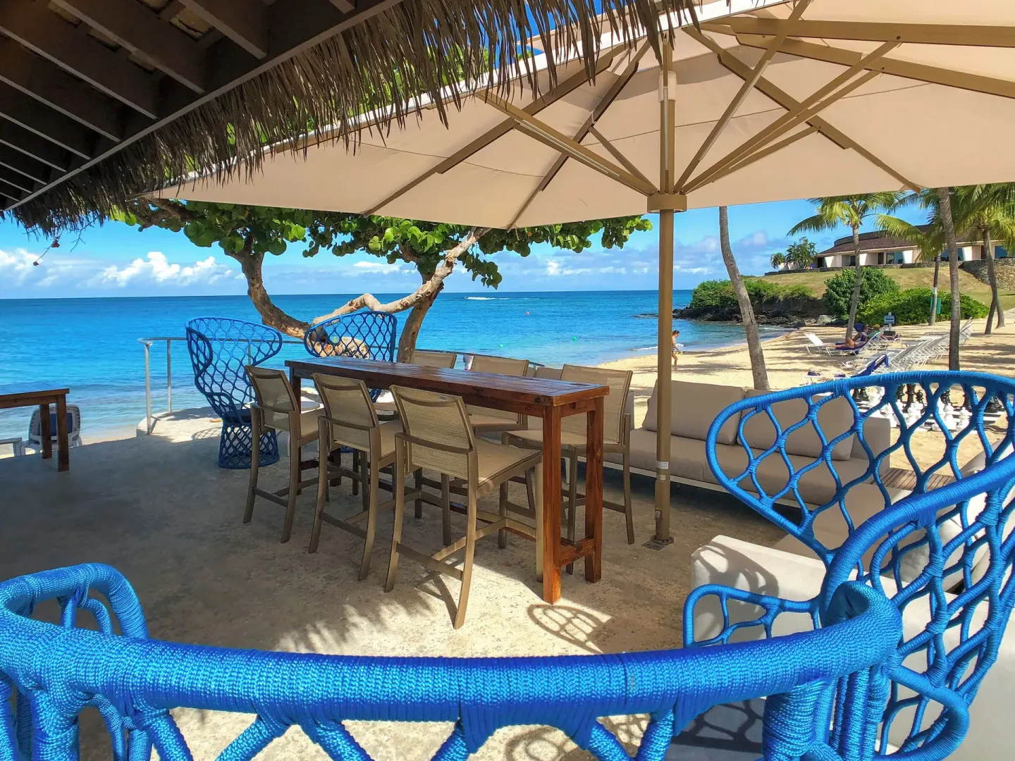 Beachfront seating and blue chairs overlook the sea at The Buccaneer Beach & Golf Resort.