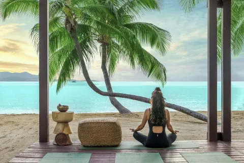 A person meditating on a beachfront deck at The Buccaneer Beach & Golf Resort.