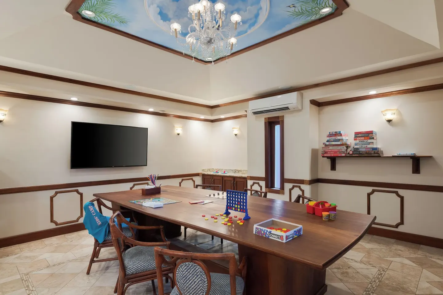 Game room with a long table, board games and wall TV at The Buccaneer Beach & Golf Resort.