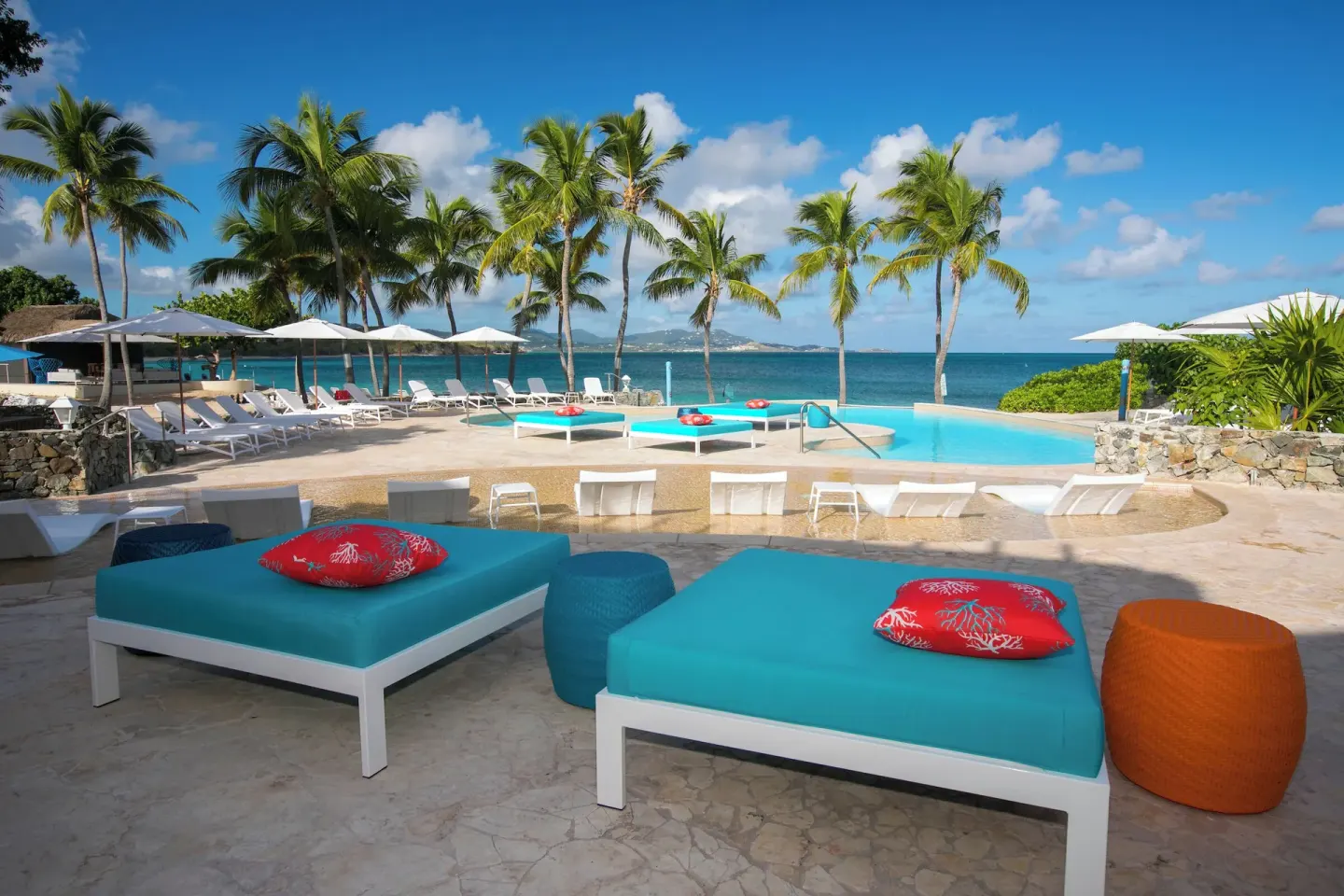 Oceanfront pool with loungers, umbrellas, and palm trees at The Buccaneer Beach & Golf Resort.