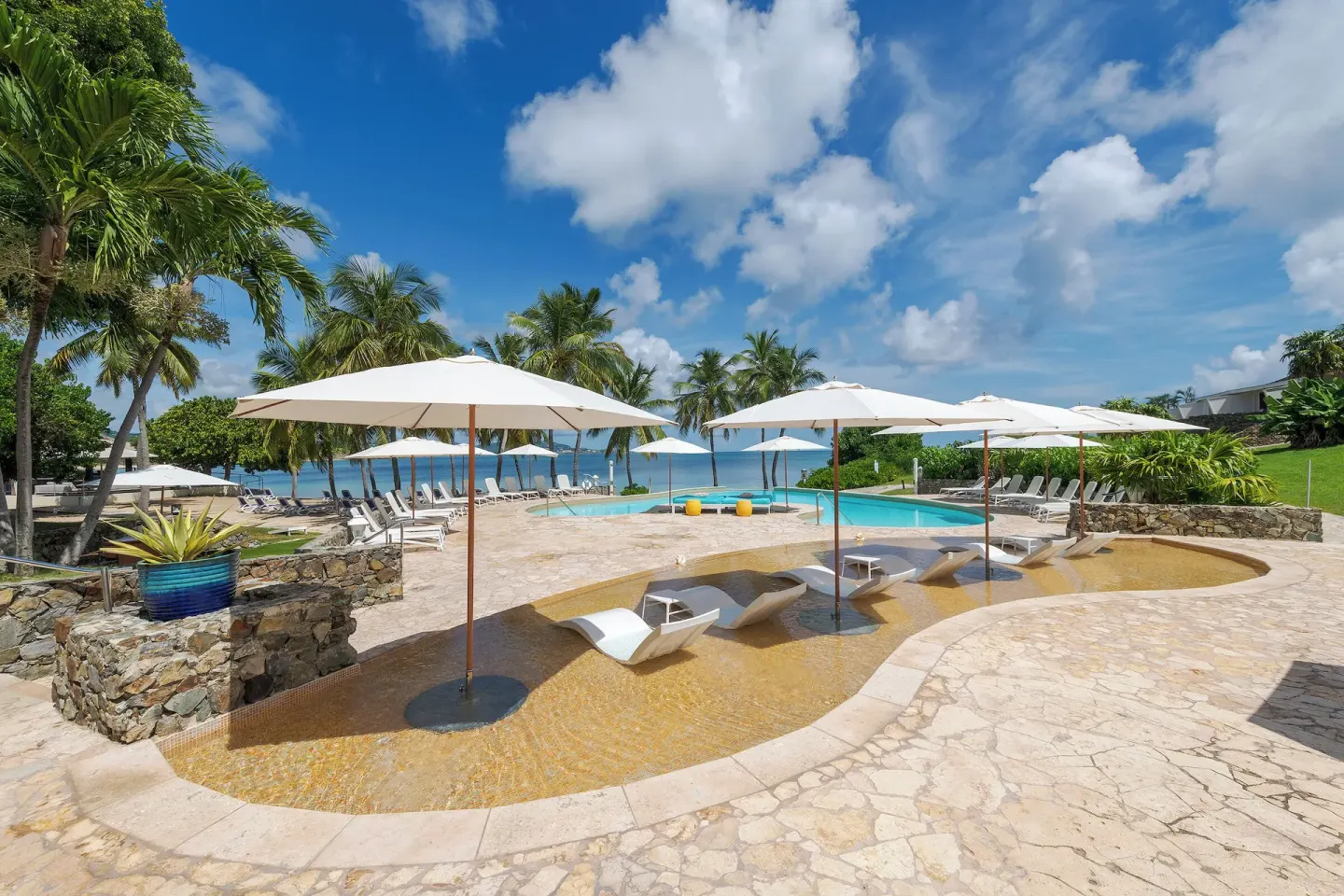 Shallow pool loungers under white umbrellas at The Buccaneer Beach & Golf Resort.