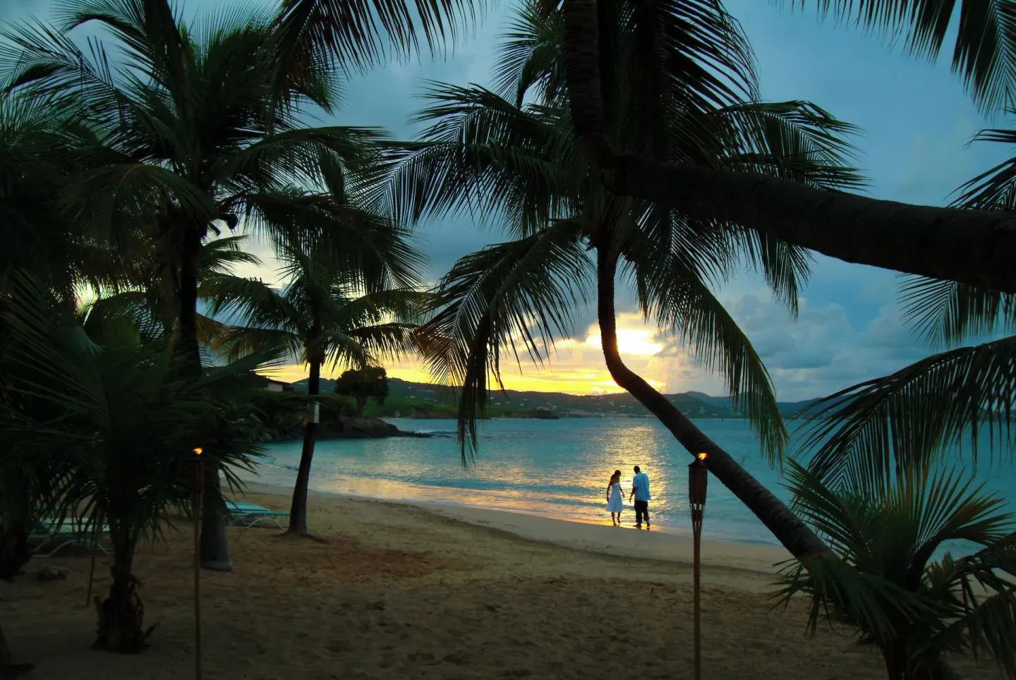 Couple standing on the beach at sunset at The Buccaneer Beach & Golf Resort.