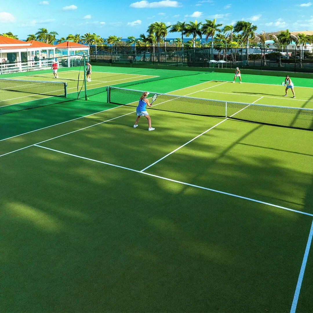 Guests play tennis on green courts at The Buccaneer Beach & Golf Resort.