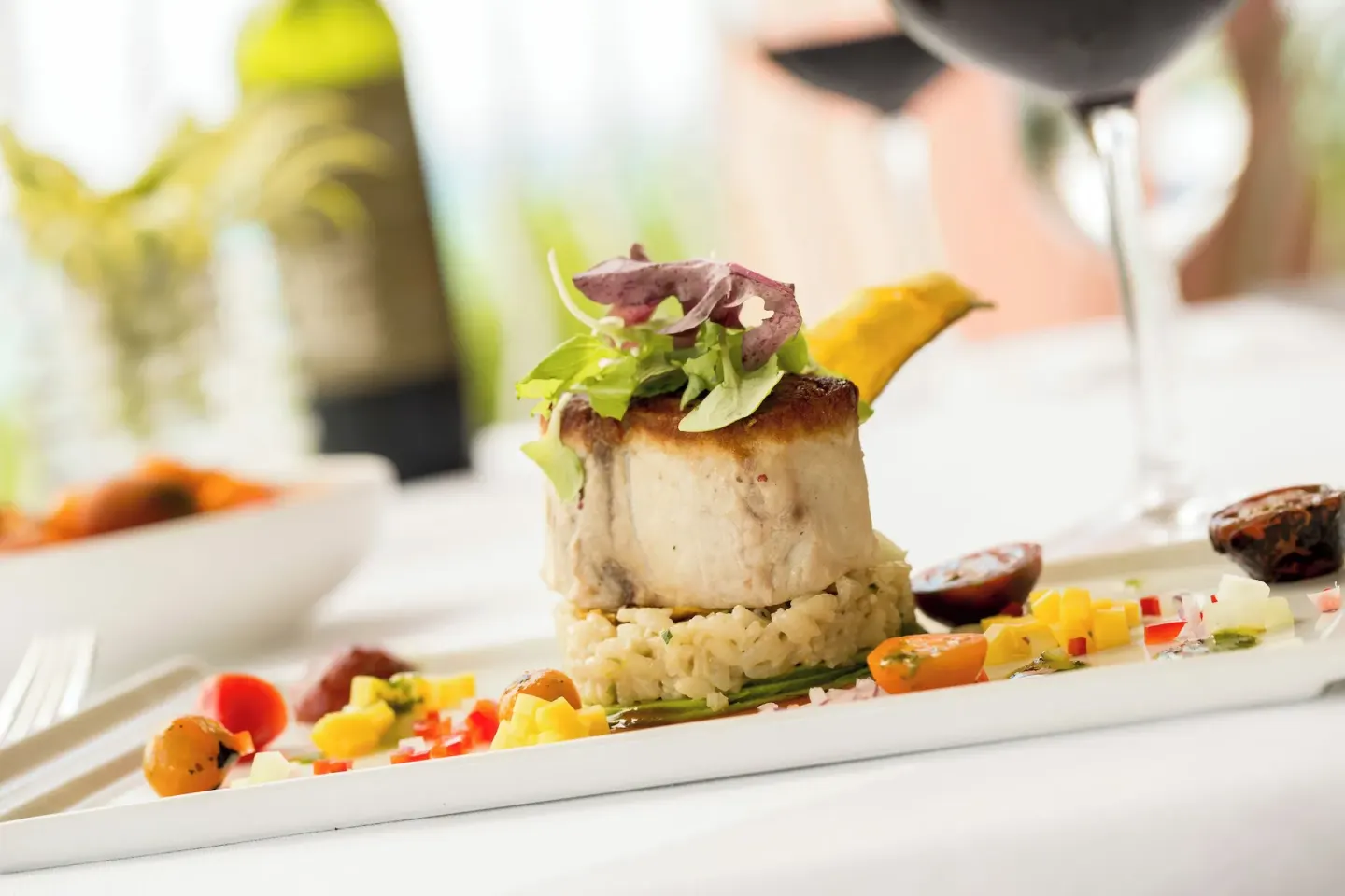 Plated fish entrée with vegetables and wine at The Buccaneer Beach & Golf Resort.