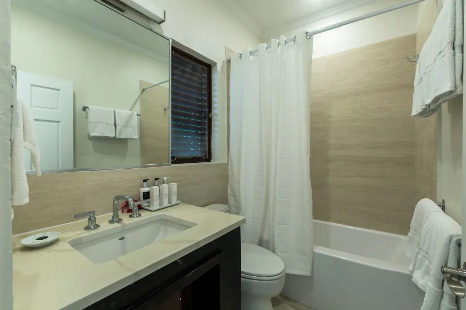 Family Cottage Suite bathroom with vanity and tub shower at The Buccaneer Beach & Golf Resort.