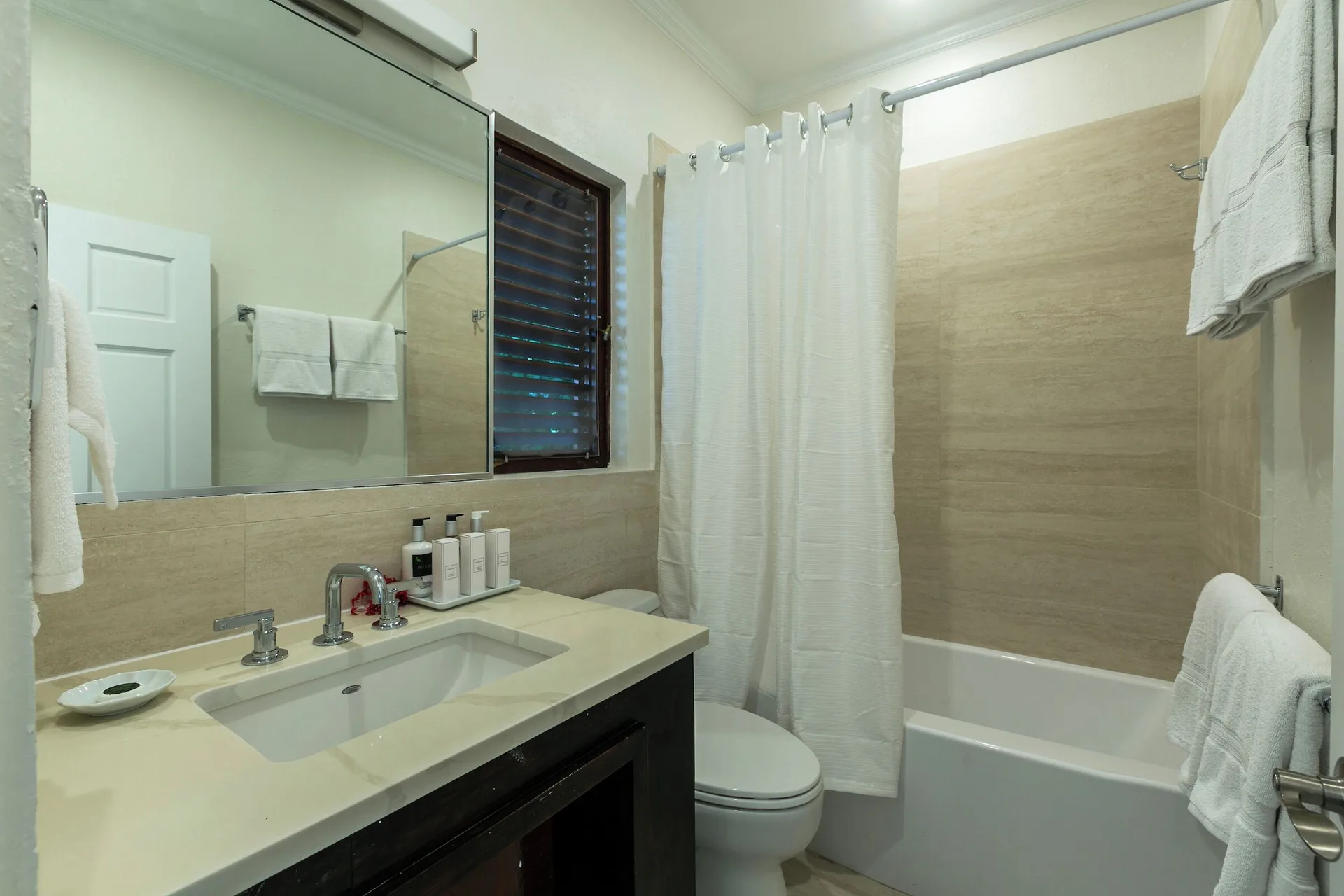 Family Cottage Suite bathroom with vanity and tub shower at The Buccaneer Beach & Golf Resort.