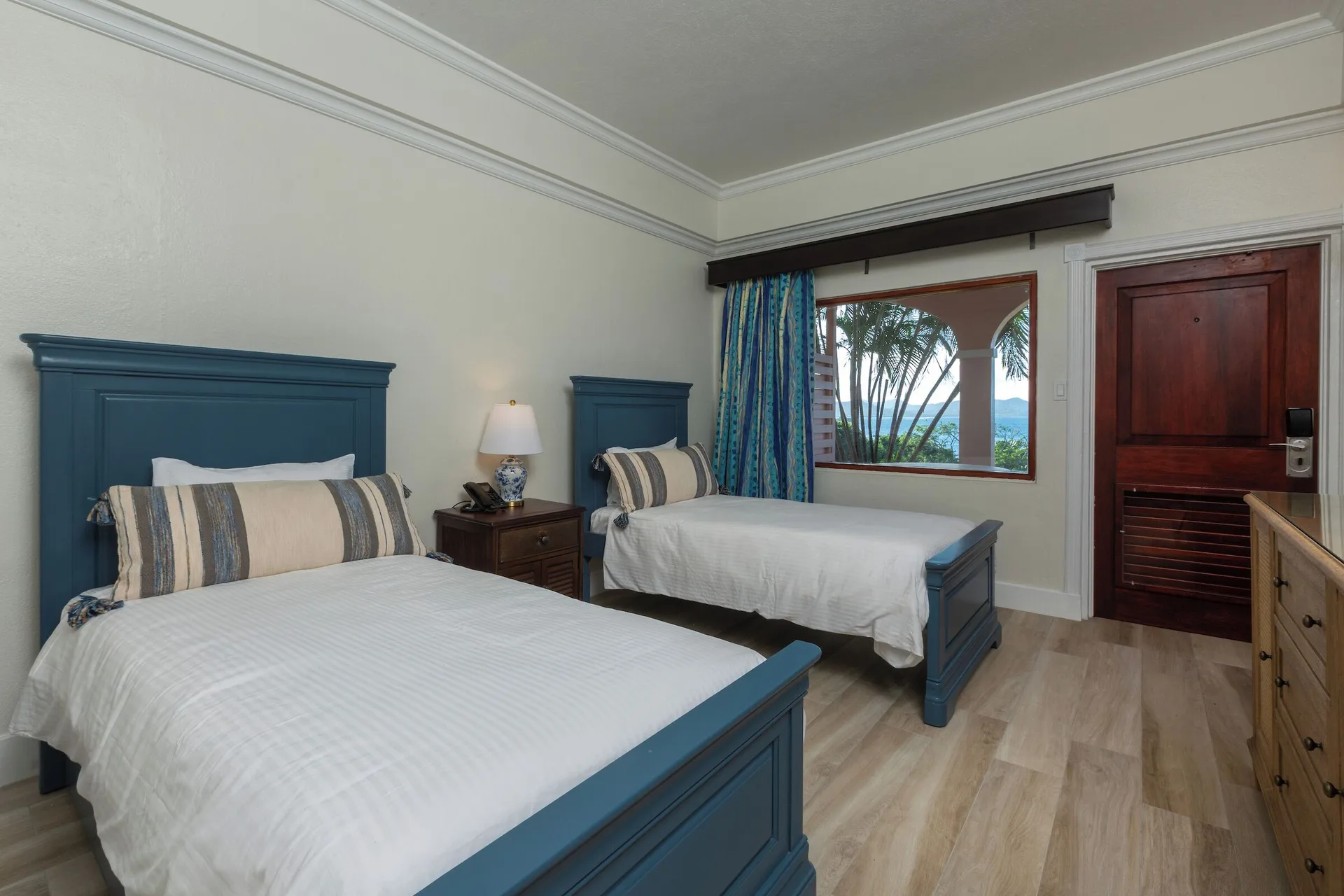 Family Cottage Suite bedroom with two beds and a window view at The Buccaneer Beach & Golf Resort.