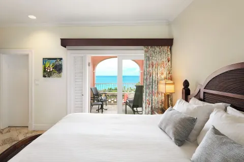Ocean View Great House king bed and balcony at The Buccaneer Beach & Golf Resort.