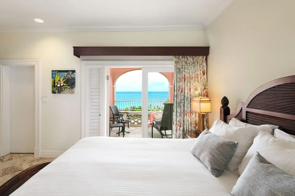 Ocean View Great House king bed and balcony at The Buccaneer Beach & Golf Resort.