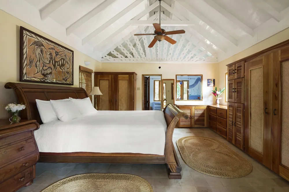 Guest room with a large wooden bed, white linens, and vaulted ceiling at The Caves.