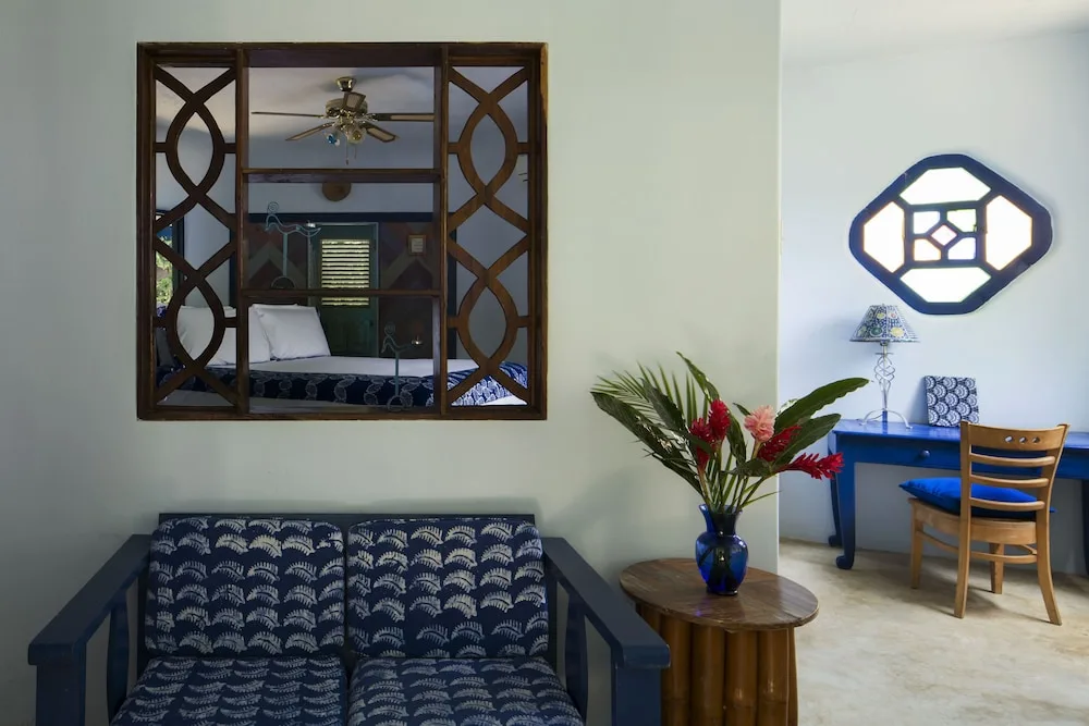 Sitting area with blue sofa, desk, and view into a bedroom at The Caves.