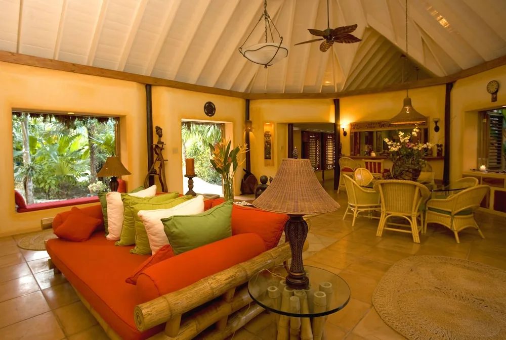 A spacious lounge and dining area with garden windows and wicker chairs at The Caves.