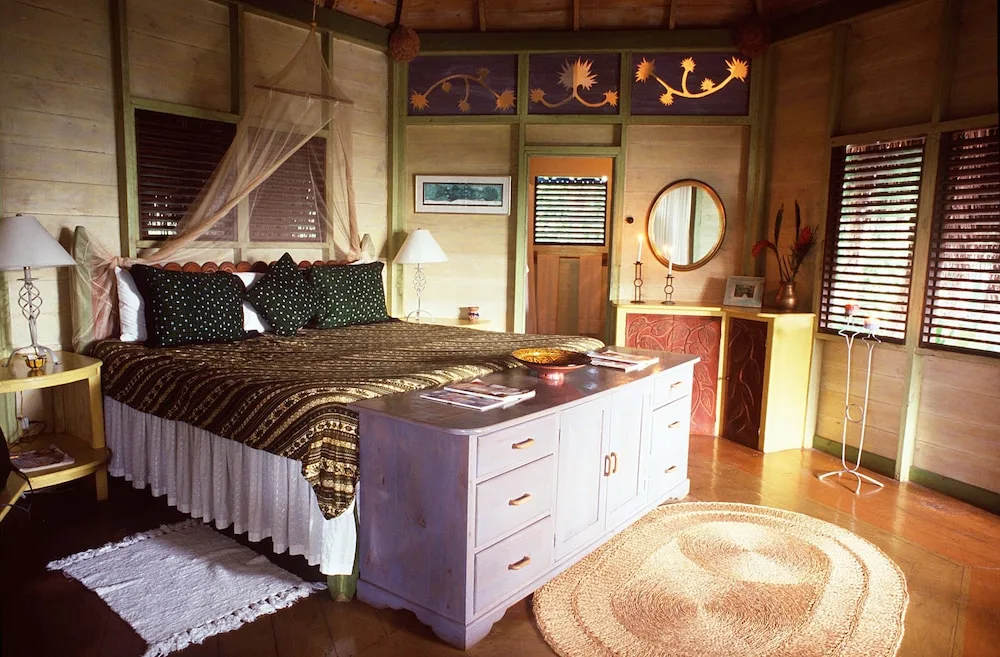 A wood-paneled guest room with a bed, dresser, and louvered windows at The Caves.