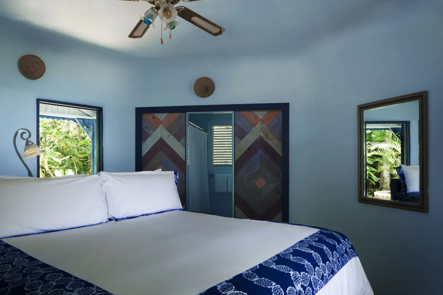 Deluxe Room king bed with blue walls and garden window at The Caves.