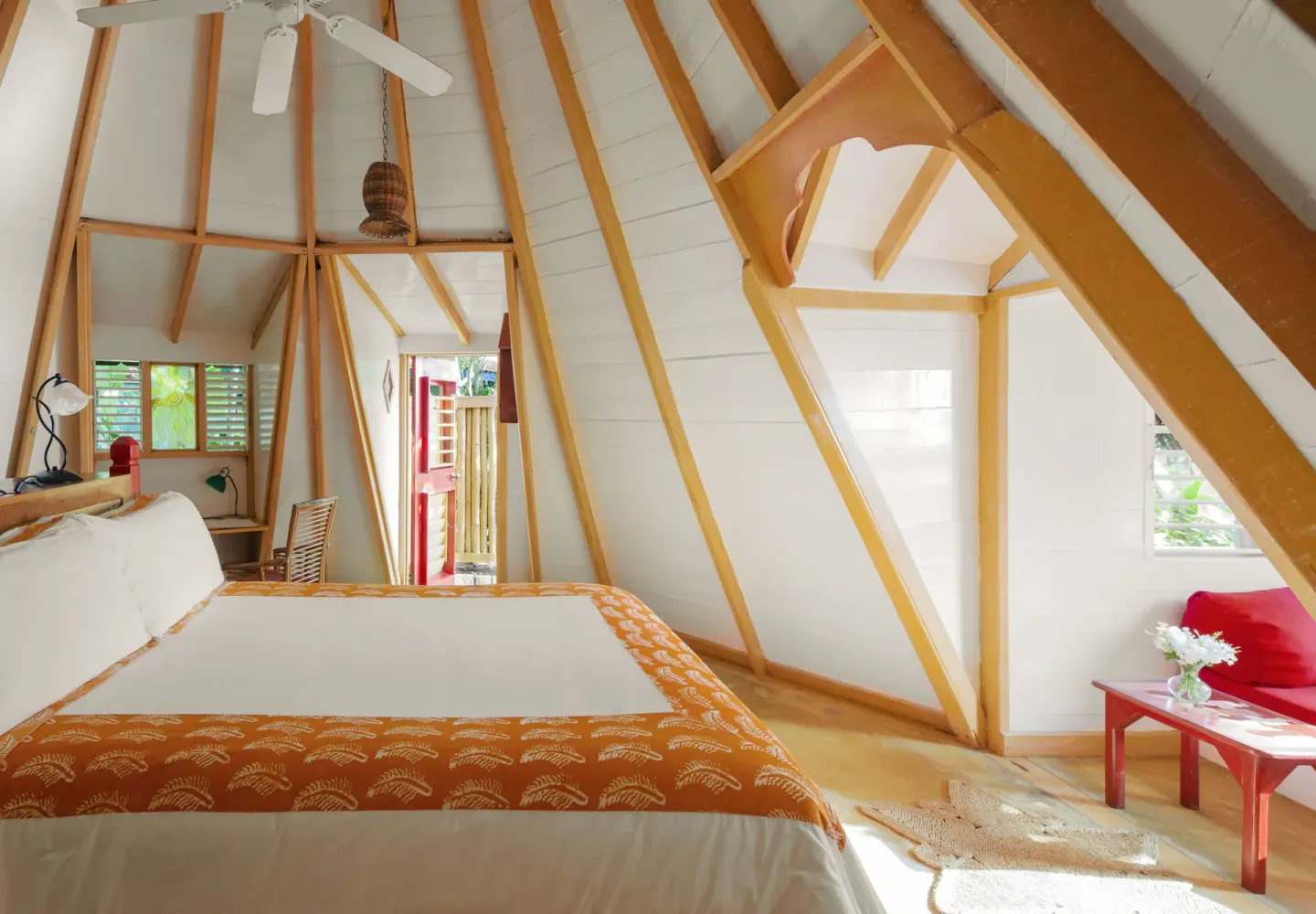 Deluxe cottage room with bed, vaulted beams, and red sitting area at The Caves.
