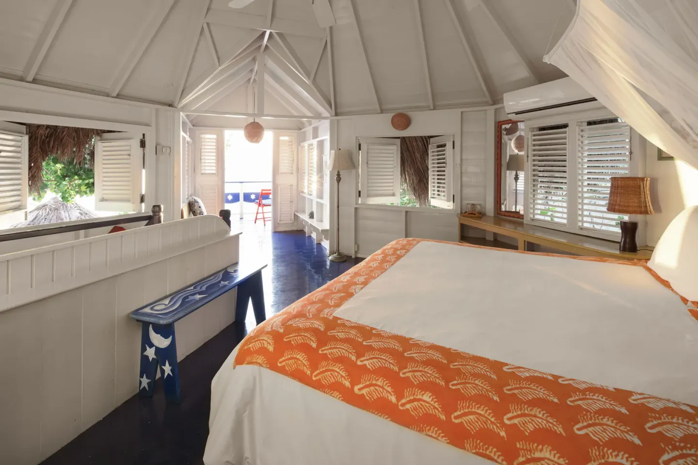 Two Bedroom Ocean View Cottage bedroom with bed and open shutters at The Caves.