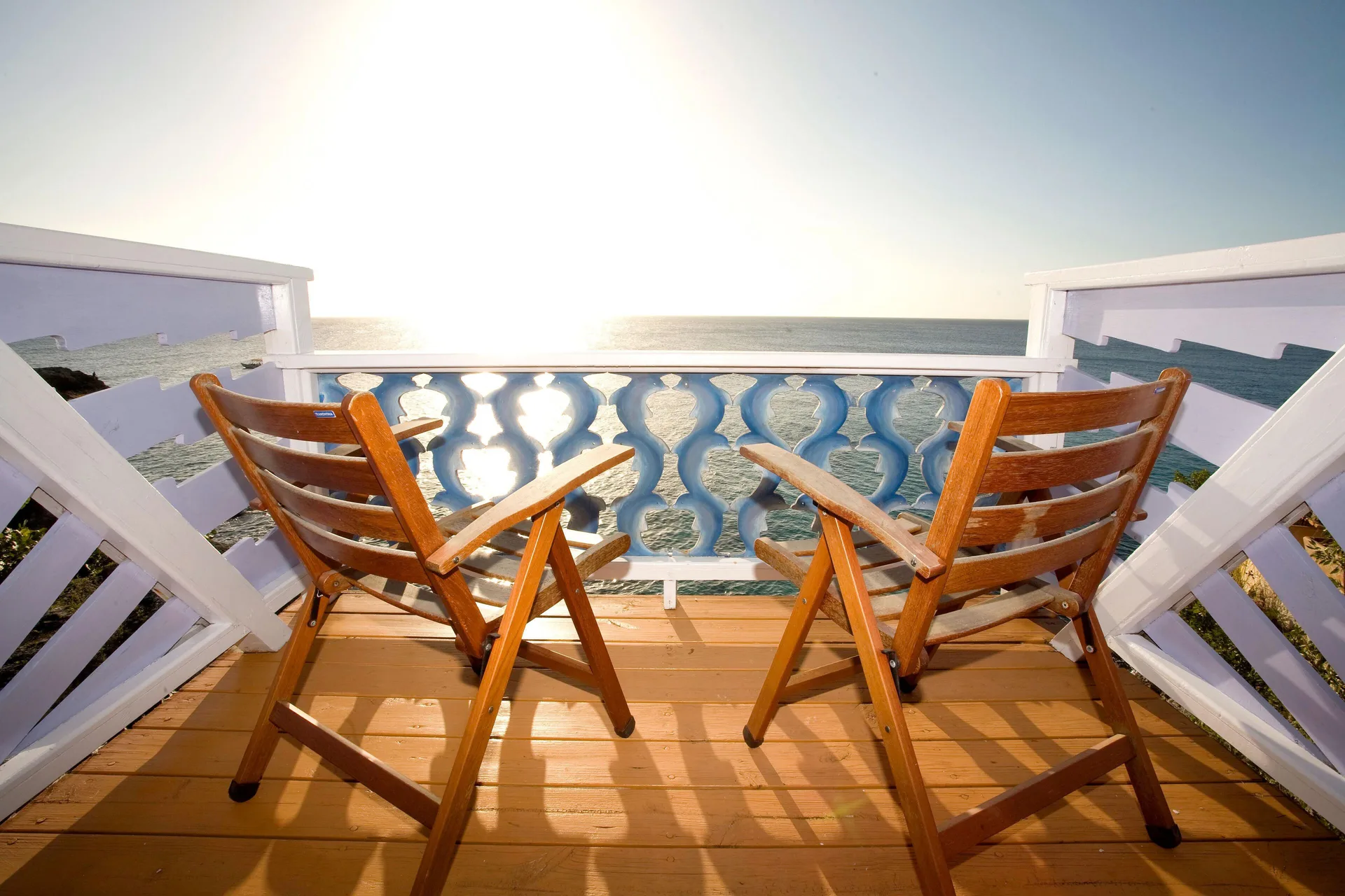 Ocean View Cottage balcony with two wooden chairs overlooking the sea at The Caves.