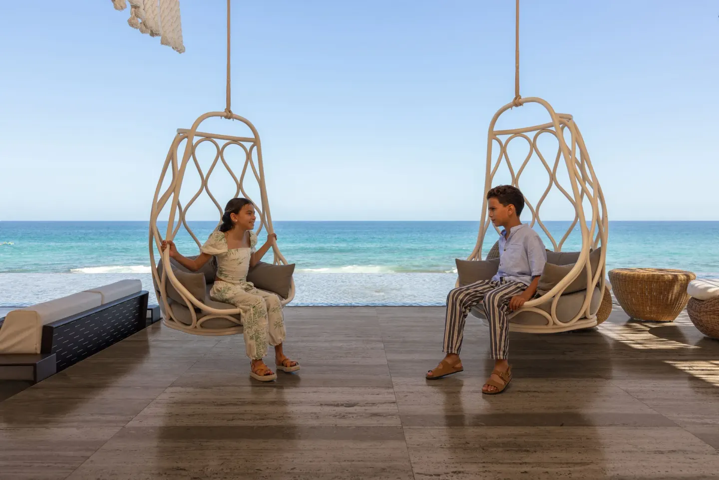 Guests sit in hanging chairs overlooking the beach at The Club at Solaz.