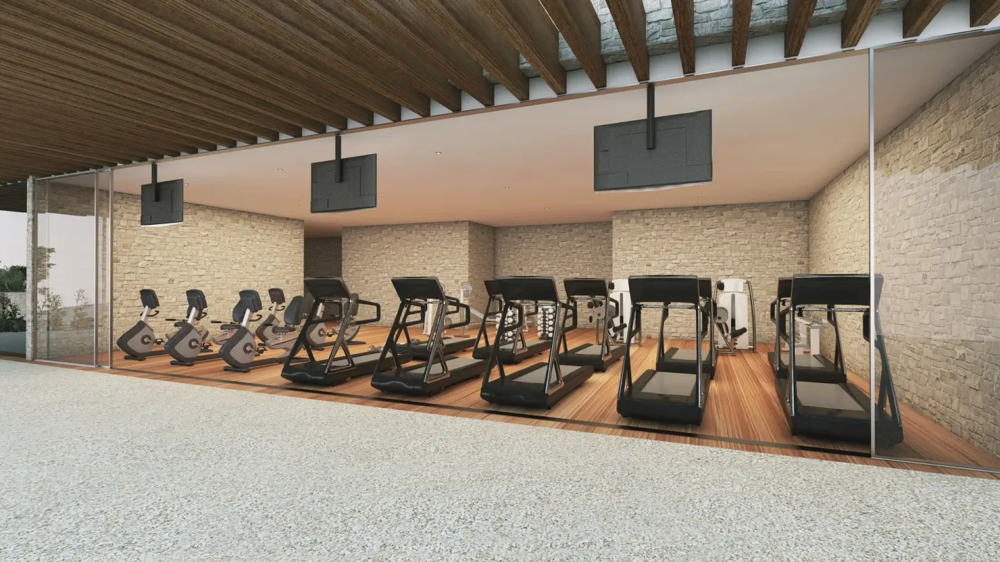 Fitness room with treadmills and bikes against stone walls at The Club at Solaz.