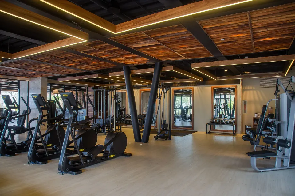 Fitness center with cardio and weight machines beneath wood ceiling panels at The Club at Solaz.