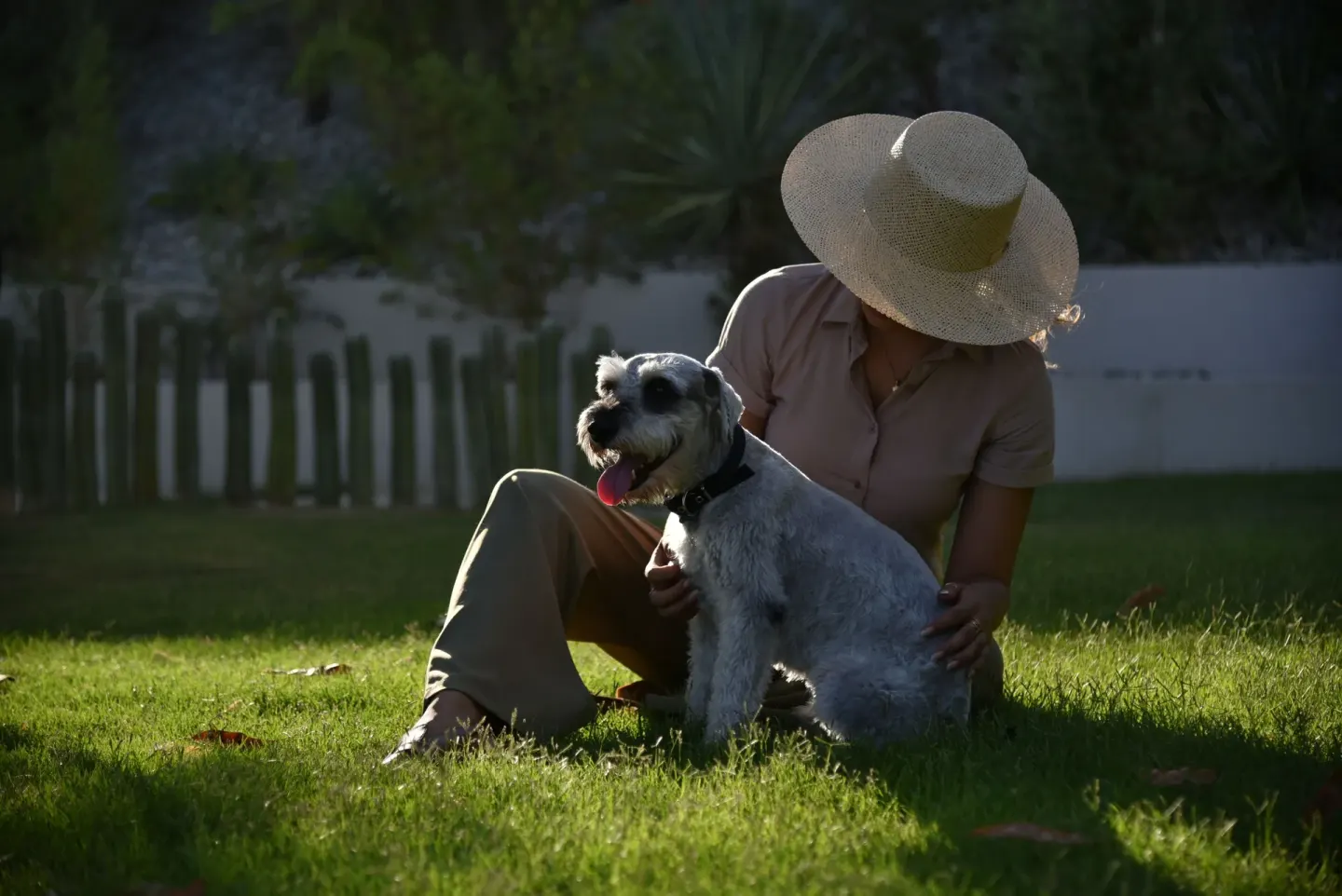 Guest sits with a small dog on the lawn at The Club at Solaz.
