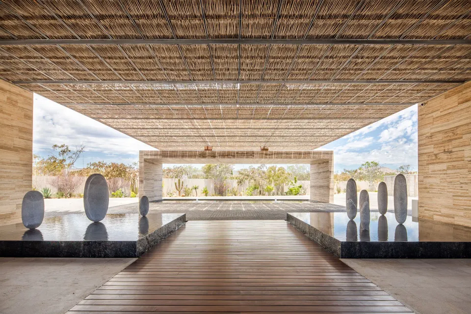 Open-air entry walkway with reflecting pools and stone sculptures at The Club at Solaz.
