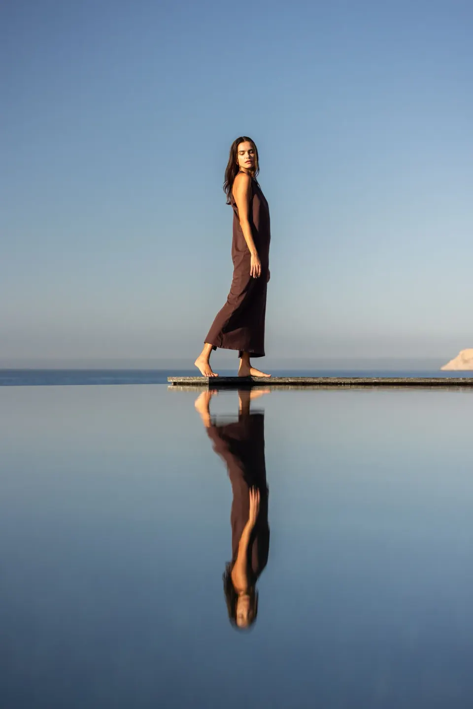 Woman walking along a narrow pool ledge with ocean beyond at The Club at Solaz.