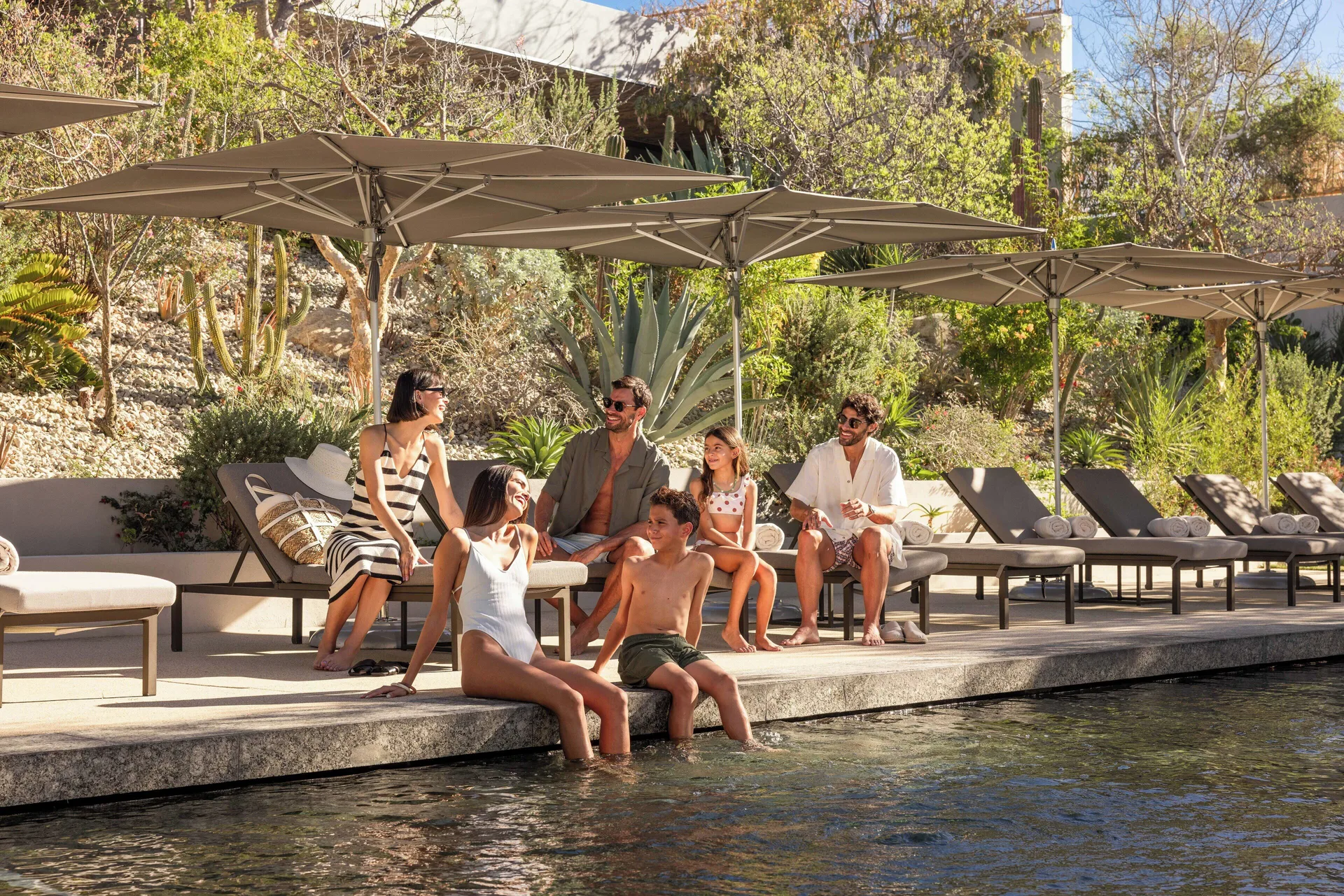 Guests relax on loungers under umbrellas by the pool at The Club at Solaz.