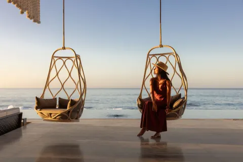 A guest sits in a hanging chair facing the ocean at The Club at Solaz.