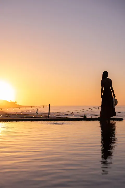 Sunset silhouette by the pool with ocean and string lights at The Club at Solaz.