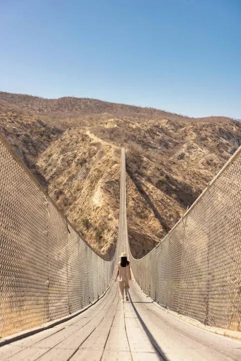 A person walks across a suspension bridge near The Club at Solaz.