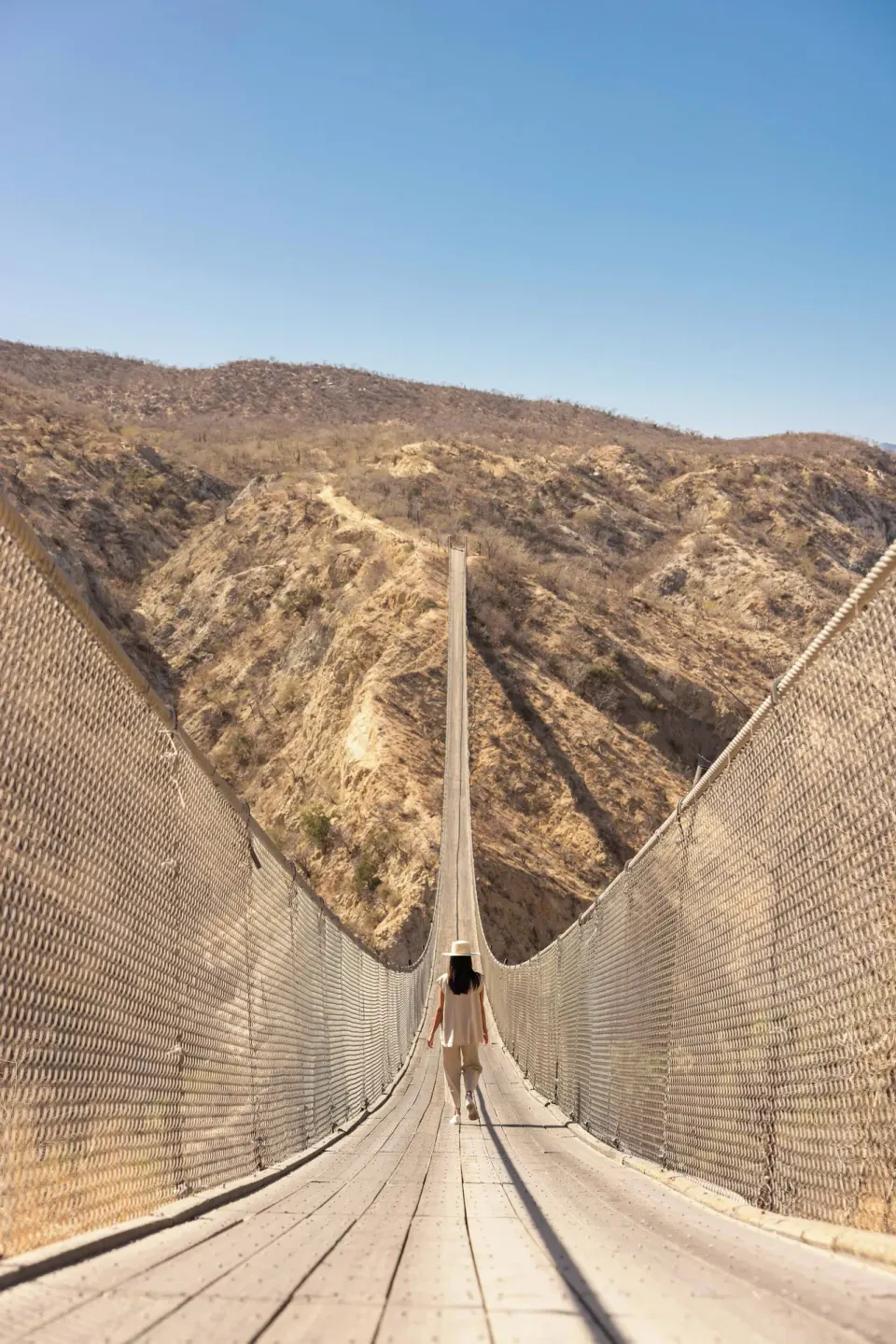 A person walks across a suspension bridge near The Club at Solaz.