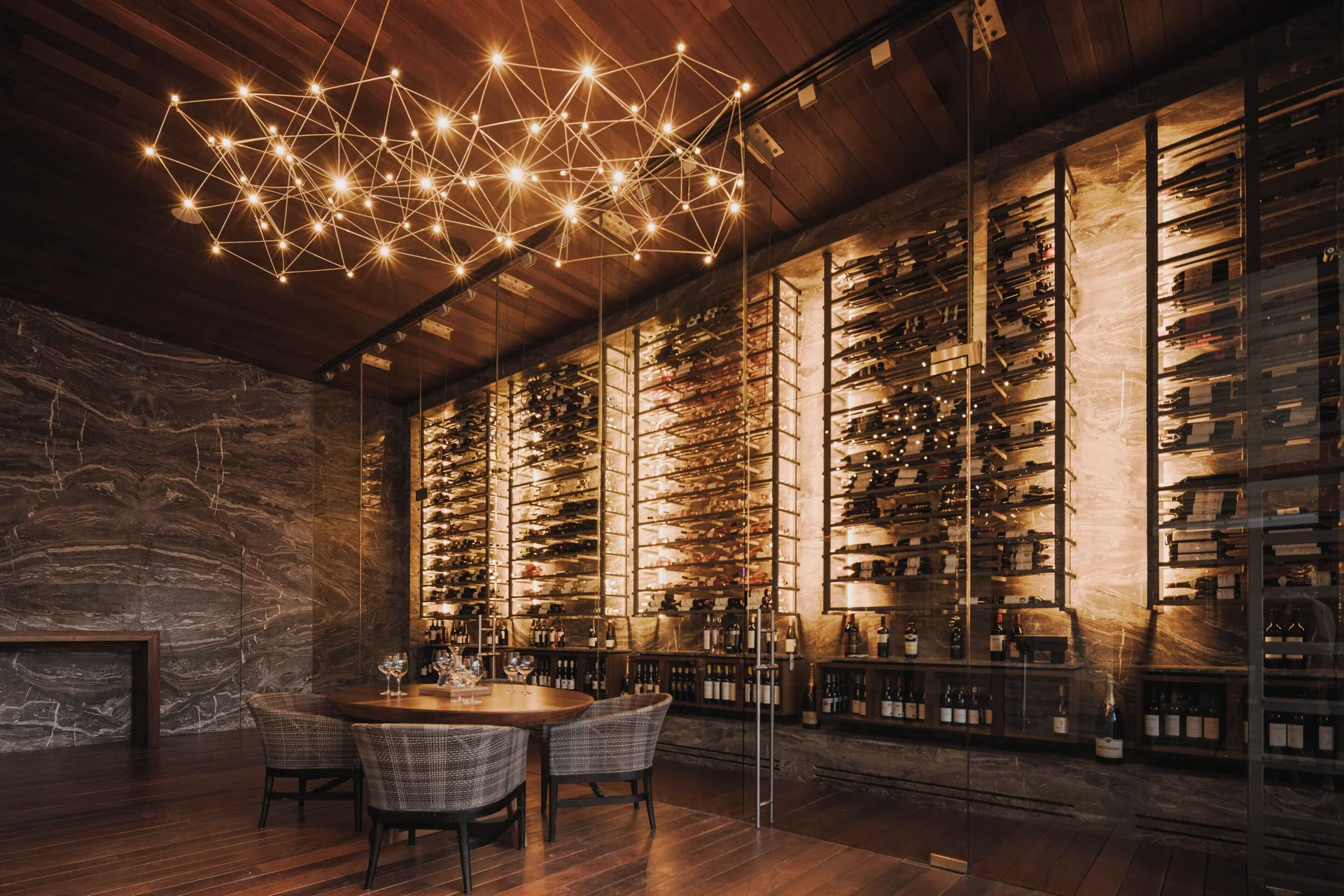 Wine room with tall bottle racks and modern chandelier at The Club at Solaz.